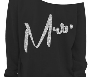 May include: Black off-the-shoulder sweatshirt with the word "Mrs." in silver glitter lettering. The sweatshirt has long sleeves and a relaxed fit. The text is in a cursive font.
