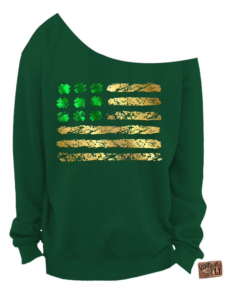 May include: A dark green off-the-shoulder sweatshirt featuring a gold and green design. The design resembles a flag with gold stripes and green shamrocks. The sweatshirt is made of a soft material and is perfect for St. Patrick's Day.