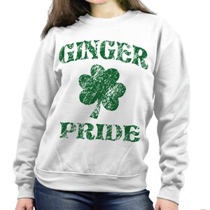 Puede incluir: Sudadera blanca con las palabras "GINGER PRIDE" en letras verdes desgastadas, junto con un tr&eacute;bol verde. La sudadera es de cuello redondo.
