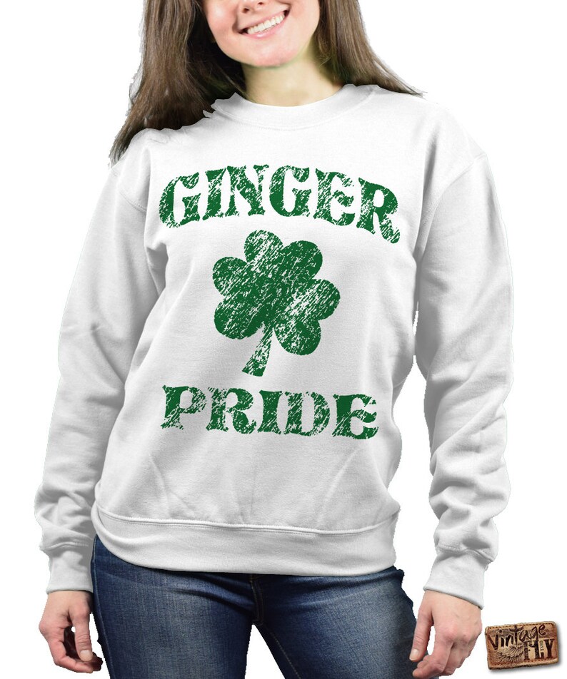 Puede incluir: Sudadera blanca con las palabras "GINGER PRIDE" en letras verdes desgastadas, junto con un tr&eacute;bol verde. La sudadera es de cuello redondo.