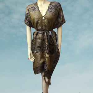 Könnte beinhalten: Eine braune und schwarze gemusterte Tunika mit V-Ausschnitt und einem Bindegürtel. Die Tunika hat einen Fransen-Saum.