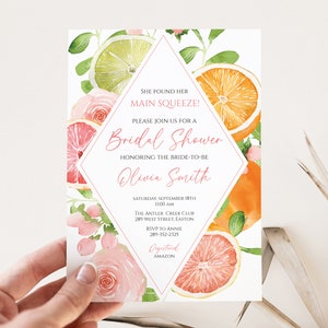 Könnte beinhalten: Eine Einladung zur Brautparty mit Aquarellillustrationen von Zitrusfrüchten und rosa Rosen. Der Einladungstext lautet "Sie hat ihren Hauptdarsteller gefunden!" und enthält den Namen der Braut, Datum, Uhrzeit und Ort.