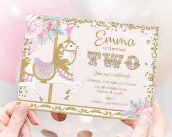 May include: Pink and gold invitation with a white carousel horse and floral accents. The text reads "Emma is turning TWO. Join us to celebrate Saturday, June 15th at 11:00 am 287 West Side Street Easton, IL. 39087 RSVP Jessie at 354-290-3902"