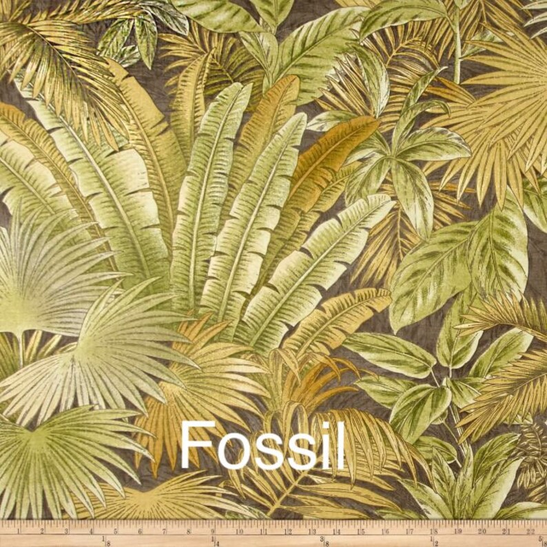 May include: A close-up of a fabric with a tropical leaf pattern in shades of green, brown, and yellow. The fabric has the word "Fossil" printed on it.
