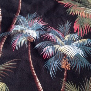 May include: Black fabric with a repeating pattern of palm trees with green, blue, white, and pink leaves. The palm trees have brown trunks and brown coconuts.