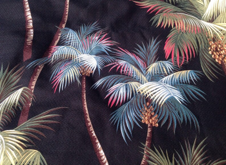 May include: Black fabric with a repeating pattern of palm trees with green, blue, white, and pink leaves. The palm trees have brown trunks and brown coconuts.