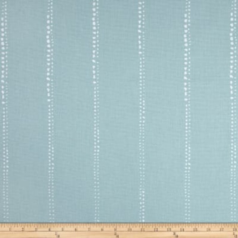 May include: A light blue fabric with a white dotted stripe pattern. The fabric is measured in inches on a ruler.