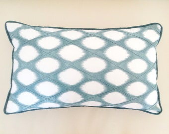 May include: A teal and white patterned throw pillow with a diamond-shaped design. The pillow has a teal border.