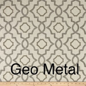 May include: Close-up of a fabric with a geometric pattern in shades of gray and beige. The design features interlocking shapes with a metallic appearance. The text "Geo Metal" is displayed in black.