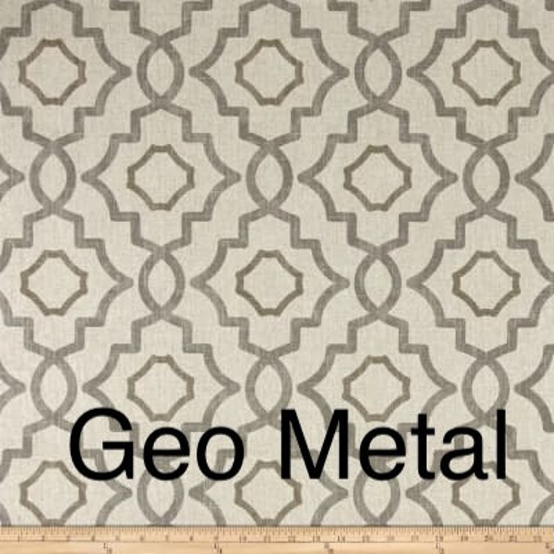 May include: Close-up of a fabric with a geometric pattern in shades of gray and beige. The design features interlocking shapes with a metallic appearance. The text "Geo Metal" is displayed in black.