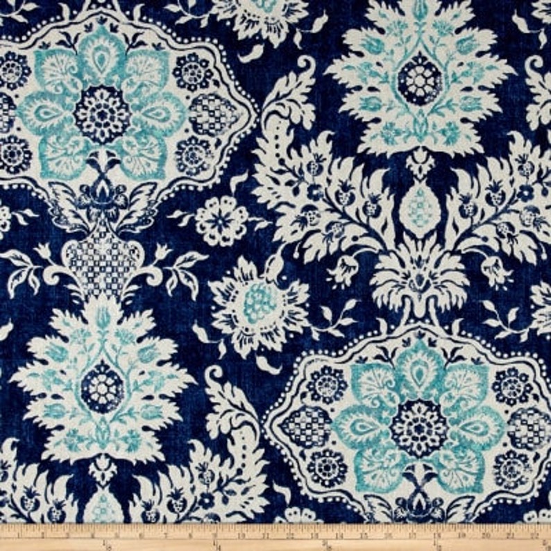 May include: Dark blue fabric with a repeating floral pattern in white and teal. The design features large, ornate floral medallions and smaller floral and leaf motifs. The fabric has a textured appearance, suggesting a woven material.