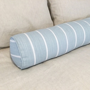 May include: A blue and white striped bolster pillow with a rounded shape. The pillow is made of a soft, textured fabric.