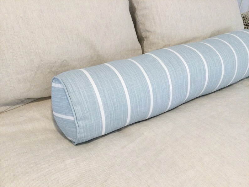 May include: A blue and white striped bolster pillow with a rounded shape. The pillow is made of a soft, textured fabric.