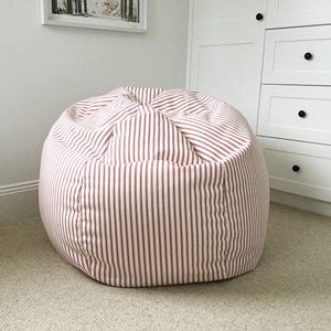 May include: A large, round beanbag chair with a white and pink striped fabric cover.