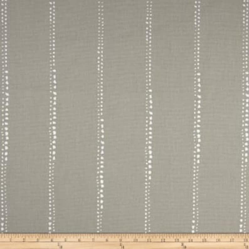 May include: A close-up of a gray fabric with white vertical stripes. The stripes are made up of small white dots.