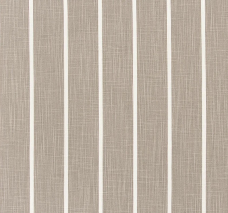 May include: A close-up of a fabric with a striped pattern. The fabric is a light brown color with white stripes.