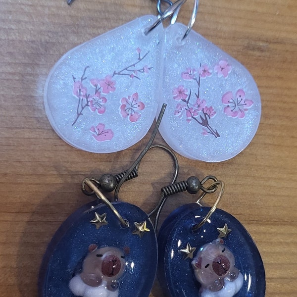 One of a kind handmade, Resin Earrings! Capybara on a cloud in starry blue sky & Cherry Blossoms/Sakura on sparkly pearl white background!