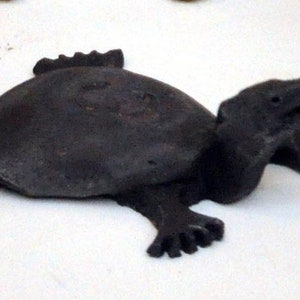 May include: A black ceramic turtle figurine with a textured shell and a slightly open mouth.