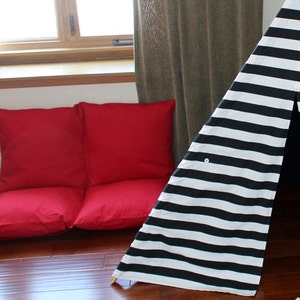 May include: A red floor lounger and a black and white striped teepee are set up indoors. The lounger is made of two square cushions. The teepee has a button closure and wooden poles.