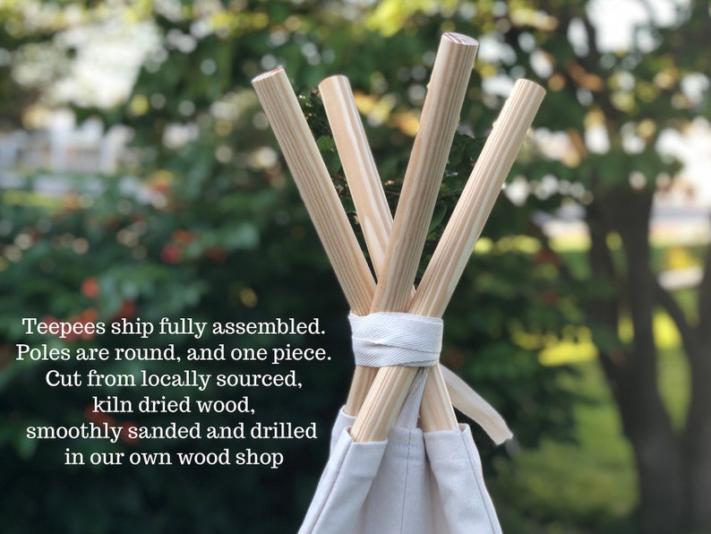 May include: Close-up of the top of a teepee tent with wooden poles. The poles are round and smooth, and they are tied together with a white fabric strap. The teepee is made of white canvas.