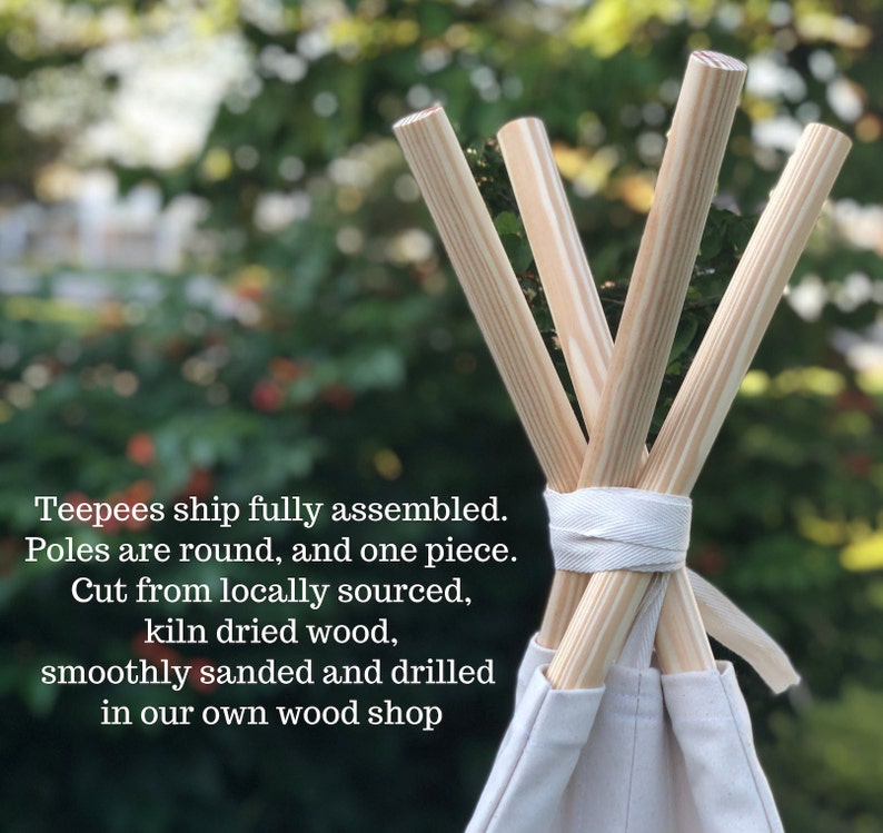 May include: Close-up of the top of a teepee tent with four wooden poles converging at the top. The poles are natural wood color and have a smooth finish. The teepee is made of white canvas fabric. The text "Teepees ship fully assembled. Poles are round, and one piece. Cut from locally sourced, kiln dried wood, smoothly sanded and drilled in our own wood shop" is visible at the bottom of the image.