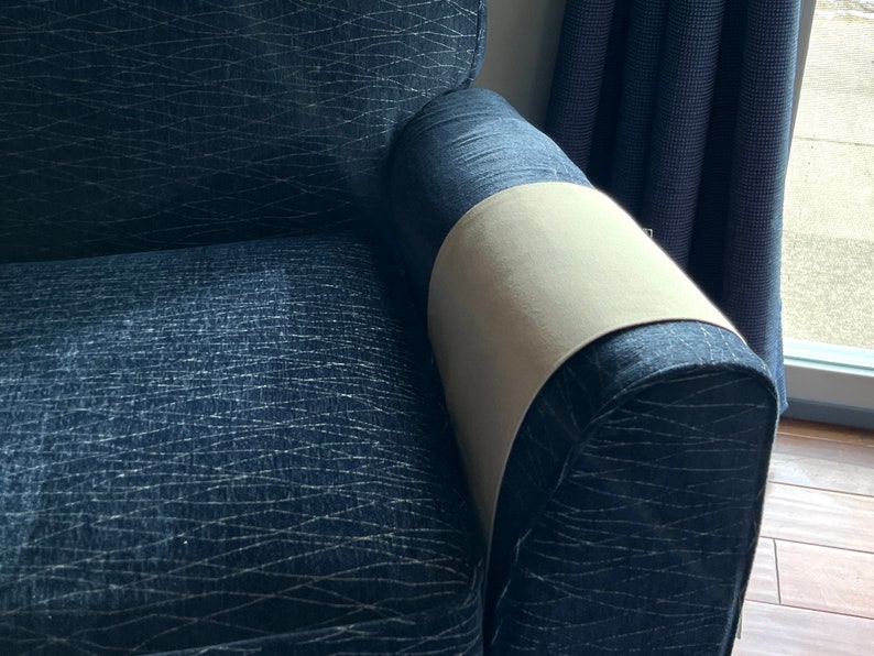 Peut inclure: Un fauteuil bleu fonc&eacute; recouvert d'un tissu &agrave; motif de lignes entrecrois&eacute;es claires. Une housse en tissu beige clair uni est pos&eacute;e sur le dessus de l'accoudoir droit, contrastant avec le rev&ecirc;tement textur&eacute; bleu fonc&eacute; du fauteuil.