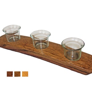 May include: A wooden candle holder made from a reclaimed wine barrel with three glass candle holders. The wood is a dark brown color with a natural wood grain.