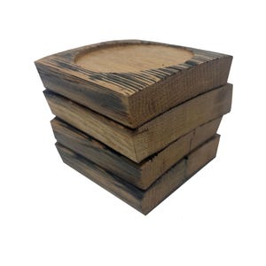 May include: Set of four brown wooden coasters with a round indentation in the center. The coasters are made from reclaimed wood and have a rustic look.