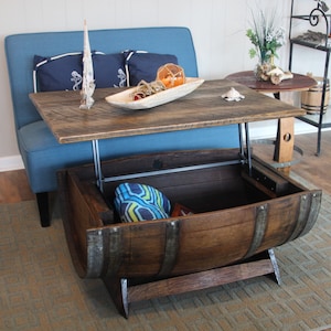 May include: A wooden barrel coffee table with a lift-top and storage space. The table is made from reclaimed wood and has a rustic finish. The top is raised to reveal a storage compartment inside the barrel.