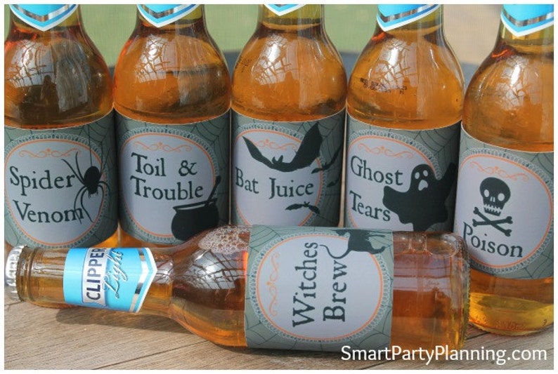 May include: Several bottles of amber-colored liquid with Halloween-themed labels. The labels feature spooky names like "Spider Venom," "Bat Juice," and "Ghost Tears." One bottle lies horizontally, labeled "Witches Brew."