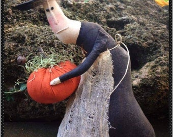 Gertie, primitive Halloween witch, holding her winner of a pumpkin