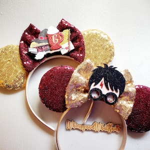 May include: Two sequined headbands with decorative elements. One features a burgundy bow with a stack of books and a mug. The other has a gold bow with a Harry Potter character design. Both have gold and burgundy sequined ears.