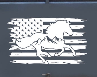 Puede incluir: Un remolque de caballos gris con una silueta blanca de un caballo corriendo a través de una cordillera y una bandera estadounidense en el fondo.