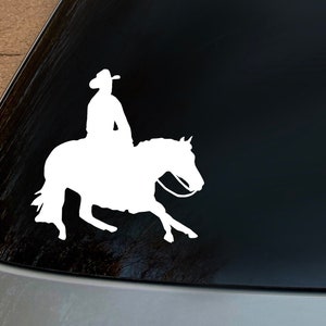May include: A white silhouette of a person riding a horse, on a black car window.