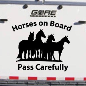 Könnte beinhalten: Weißer Pferdeanhänger mit einer schwarzen Silhouette von vier Pferden und dem Text "Horses on Board" und "Pass Carefully".