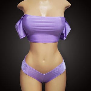 Peut inclure: Un haut court à épaules dénudées et un short taille haute assorti de couleur lavande. Le haut a des manches courtes et bouffantes et le short a un devant en forme de V.