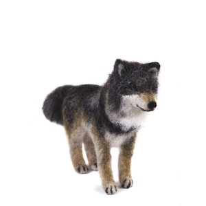 May include: A needle felted wolf figurine with a black and gray coat, brown legs, and a white chest. The wolf is standing on a white background.