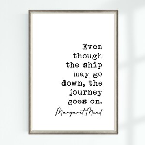 May include: Framed print with a quote by Margaret Mead: "Even though the ship may go down, the journey goes on." The text is in black, typewriter-style font on a white background, framed in a silver-toned frame.