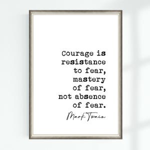 May include: Framed print with a quote by Mark Twain: "Courage is resistance to fear, mastery of fear, not absence of fear." The text is in black on a white background, framed in a silver-tone frame. A motivational piece.