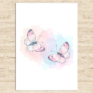 May include: Watercolor illustration of two butterflies with pink and blue wings. The butterflies are set against a soft, pastel-colored background of pink, blue, and purple hues. The artwork is on a white background.