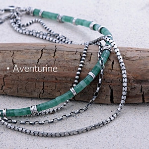 May include: A multi-strand necklace featuring green aventurine cylindrical beads accented with silver-toned metal spacers and various silver-toned chain links. The word Aventurine is printed in white text on the left side of the image.