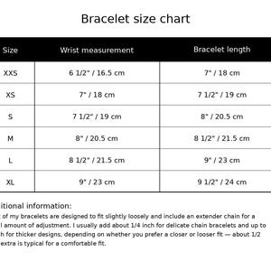 May include: A black and white bracelet size chart table listing sizes from XXS to XL with corresponding wrist measurements and bracelet lengths in inches and centimeters. Includes additional text regarding extender chain adjustments.