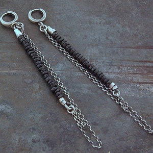 May include: A pair of long silver chain earrings with black beads. The earrings have a hoop at the top and dangle down with a chain and beads.