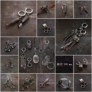 May include: A selection of handcrafted silver earrings in diverse styles. The earrings include hoops, dangles, studs, and chandelier designs. Some feature textured metal, gemstones, and unique shapes. The jewellery is displayed on a dark, textured surface.