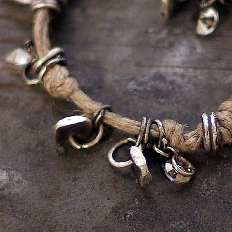 Detail view of the oxidized silver surface and linen texture of a boho bracelet. Brushed and hammered finishes reveal warm gray tones against the natural beige linen. Designed in a raw, rustic aesthetic that merges earthy materials with elegant craftsmanship — a symbolic piece of handmade jewelry celebrating authenticity and transformation.