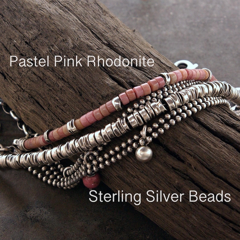 May include: A multi-strand bracelet featuring pastel pink rhodonite disc beads and sterling silver beads. The design includes small silver spheres, flat silver spacers, and a single dangling silver charm. Text reads: Pastel Pink Rhodonite Sterling Silver Beads.