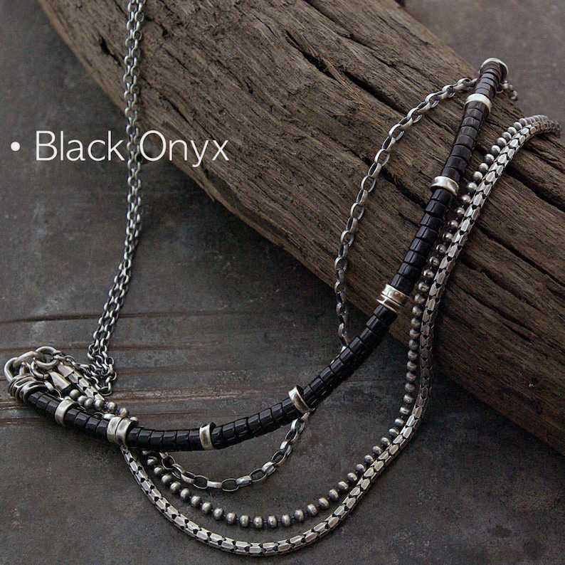 Op de afbeelding: Een meerstrengs ketting met een zilveren ketting, een streng zwarte onyx kralen met zilveren tussenstukjes, een fijne schakelketting en een zilveren kralenketting. De tekst Black Onyx is zichtbaar aan de linkerkant van de afbeelding.