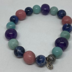 May include: A multi-coloured beaded bracelet with a silver charm. The beads are pink, blue, green, and purple. The charm has the letter "C" and the number "925" on it.