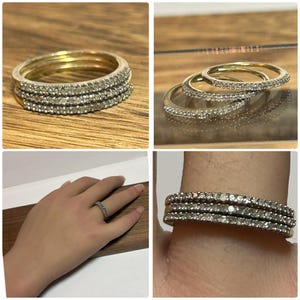 May include: Stackable gold rings with clear gemstones. The rings are shown in multiple views, including a close-up of the rings stacked together, and a single ring on a finger. The rings are on a wooden surface.