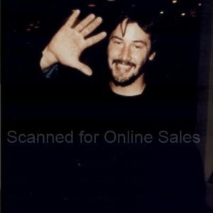 May include: A photograph of a person with dark hair and a beard, wearing a black shirt, waving with an open hand. The image features the text Scanned for Online Sales overlaid across the center. The lighting is dim, highlighting the facial features.